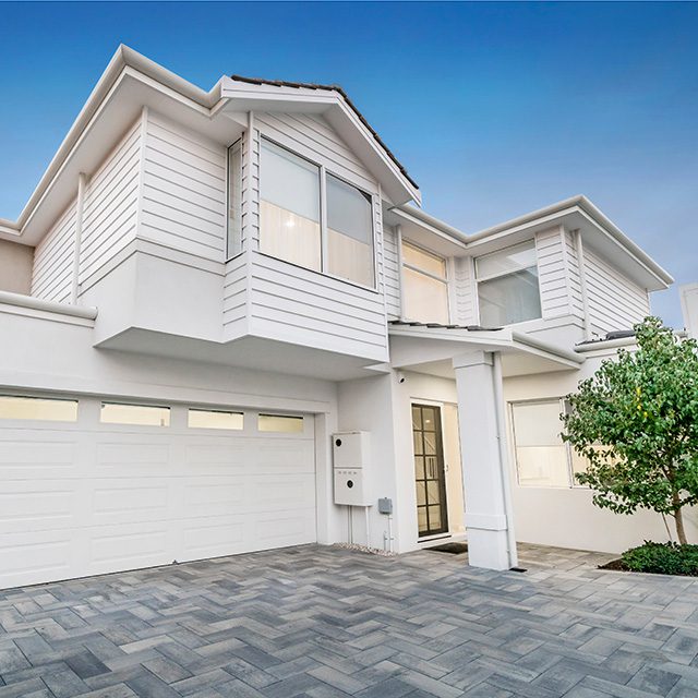 White two story house with paved driveway and small tree at front door