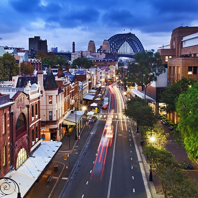 australia sydney the rocks historic district in the city view from top on george street illuminated houses and Sydney Bridge in the background at sunset
