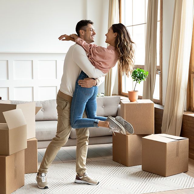Happy young husband lifting excited wife celebrating moving day